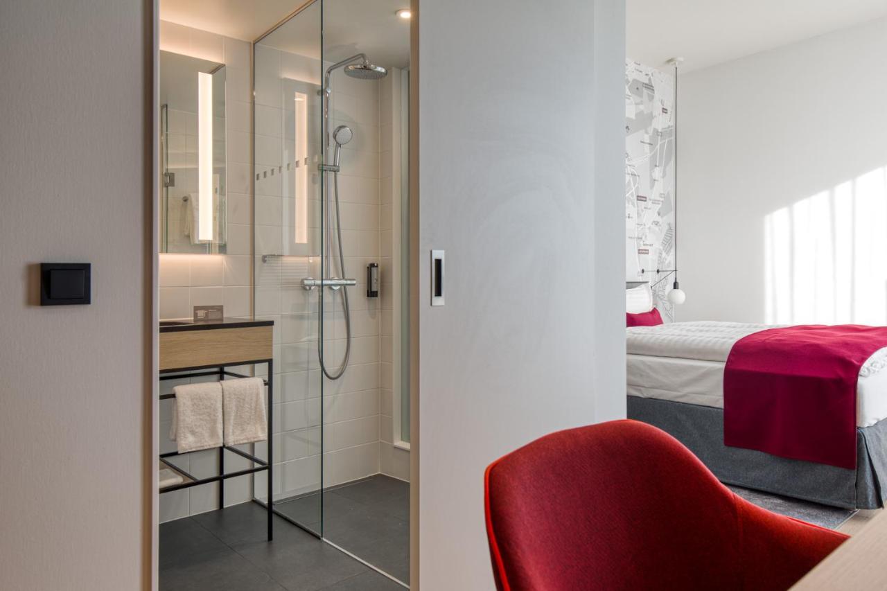 Intercityhotel Berlin Airport Ber Terminal 1 & 2 シェーネフェルト エクステリア 写真 The photo shows a modern hotel room or bathroom space. On the left, there is a glass-enclosed shower area with a sleek design, featuring a showerhead and minimalist fixtures. Adjacent to the shower, there's a sink area with a stylish countertop and a